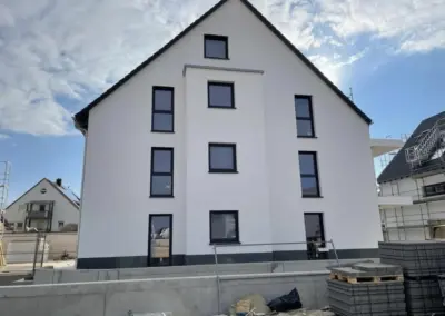 Weißer Fassadenanstrich an einem Neubau-Mehrfamilienhaus