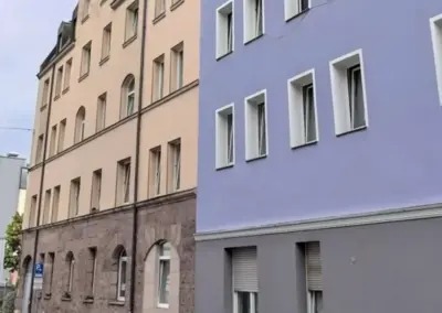 Frisch gestrichener Altbau neben ungestrichener Fassade im direkten Vergleich