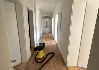 Fertig gestrichener Flur mit weißen Wänden und Parkettboden