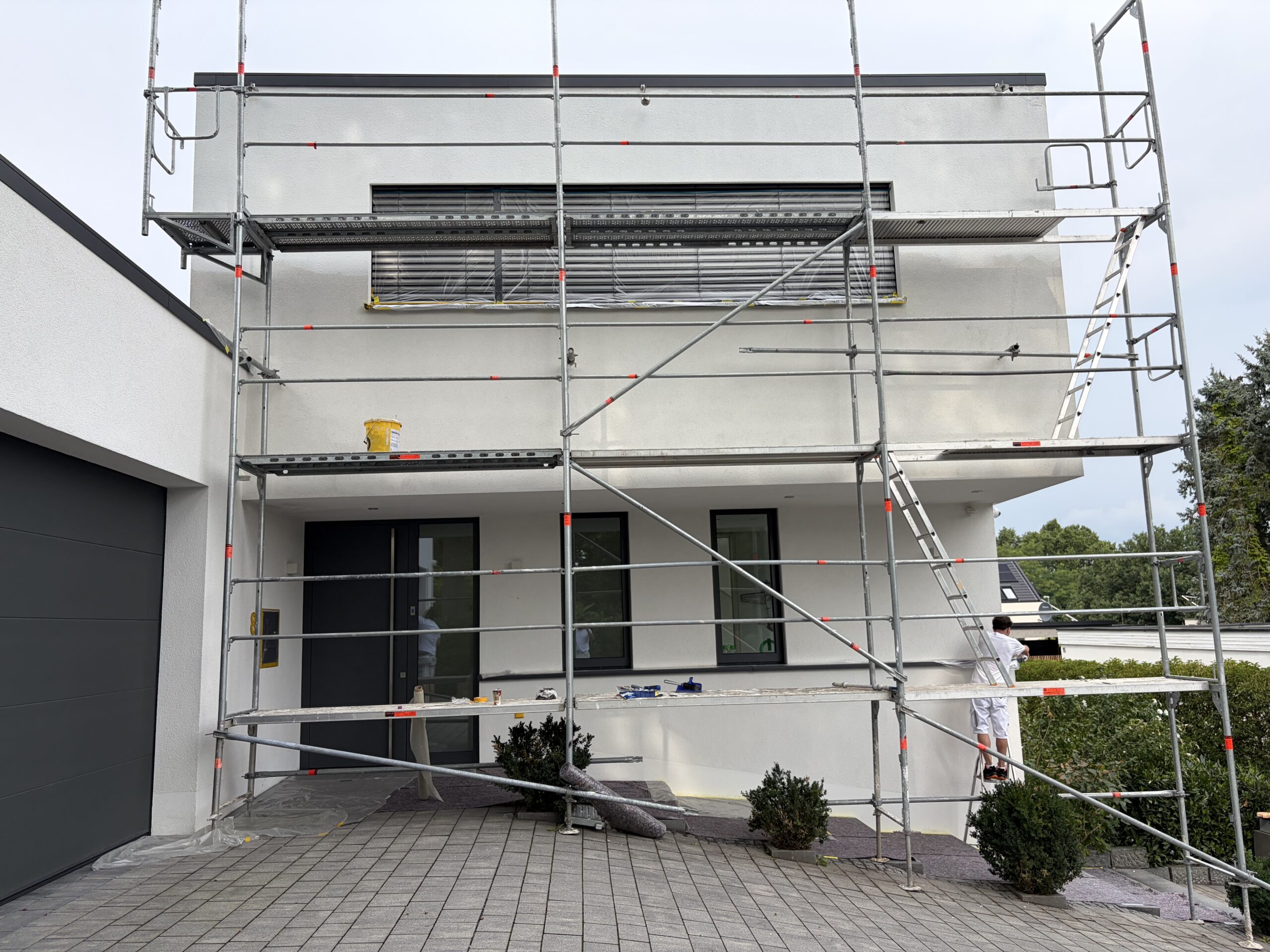 Maler in Nürnberg beim professionellen Streichen einer Hausfassade mit Gerüst<br />
