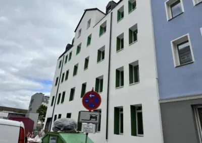 Mehrfamilienhaus mit frisch gestrichener Fassade und farbigen Fensterlaibungen
